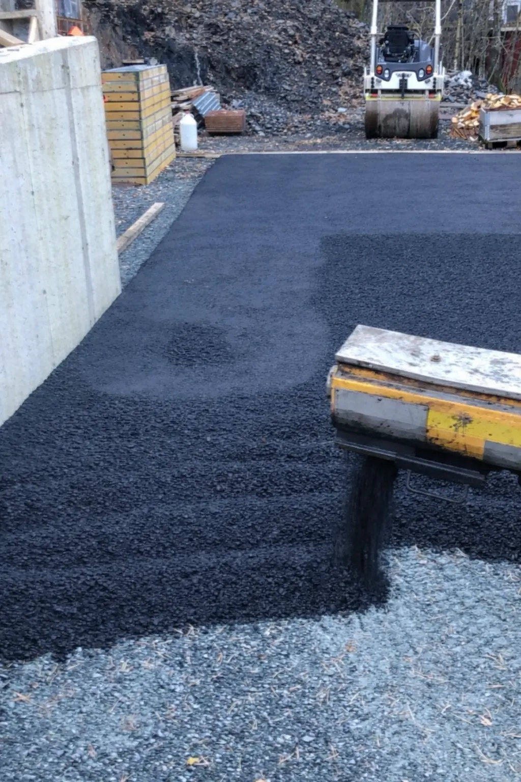 Asfaltlegging i Bergen med spreeder og nytt asfaltdekke på vei eller plass